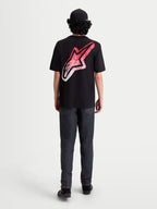 Alpinestars Maglietta Meteor CSF, maglietta a maniche corte nera, vista posteriore su modello con grande logo Astars sulla schiena, grafica sfumata rossa e bianca d'ispirazione MX, stile sportswear casual motorsport.