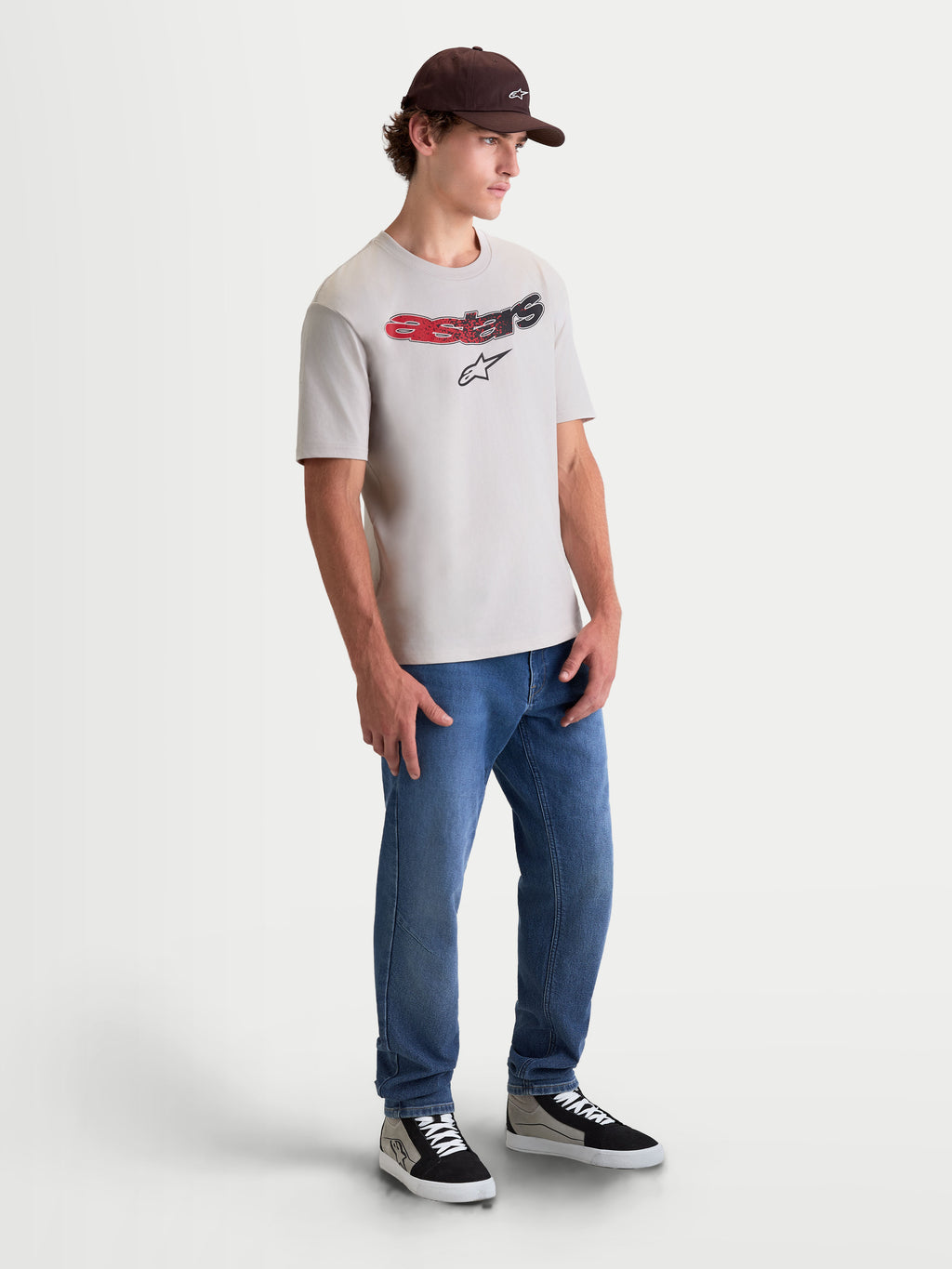Alpinestars Maglietta Elliptogrit CSF, maglietta a maniche corte sportswear da uomo, grigio cemento, con grafica Astars curva e sfumatura rossa e nera, foto a figura intera su modello per un look casual ispirato al motorsport.