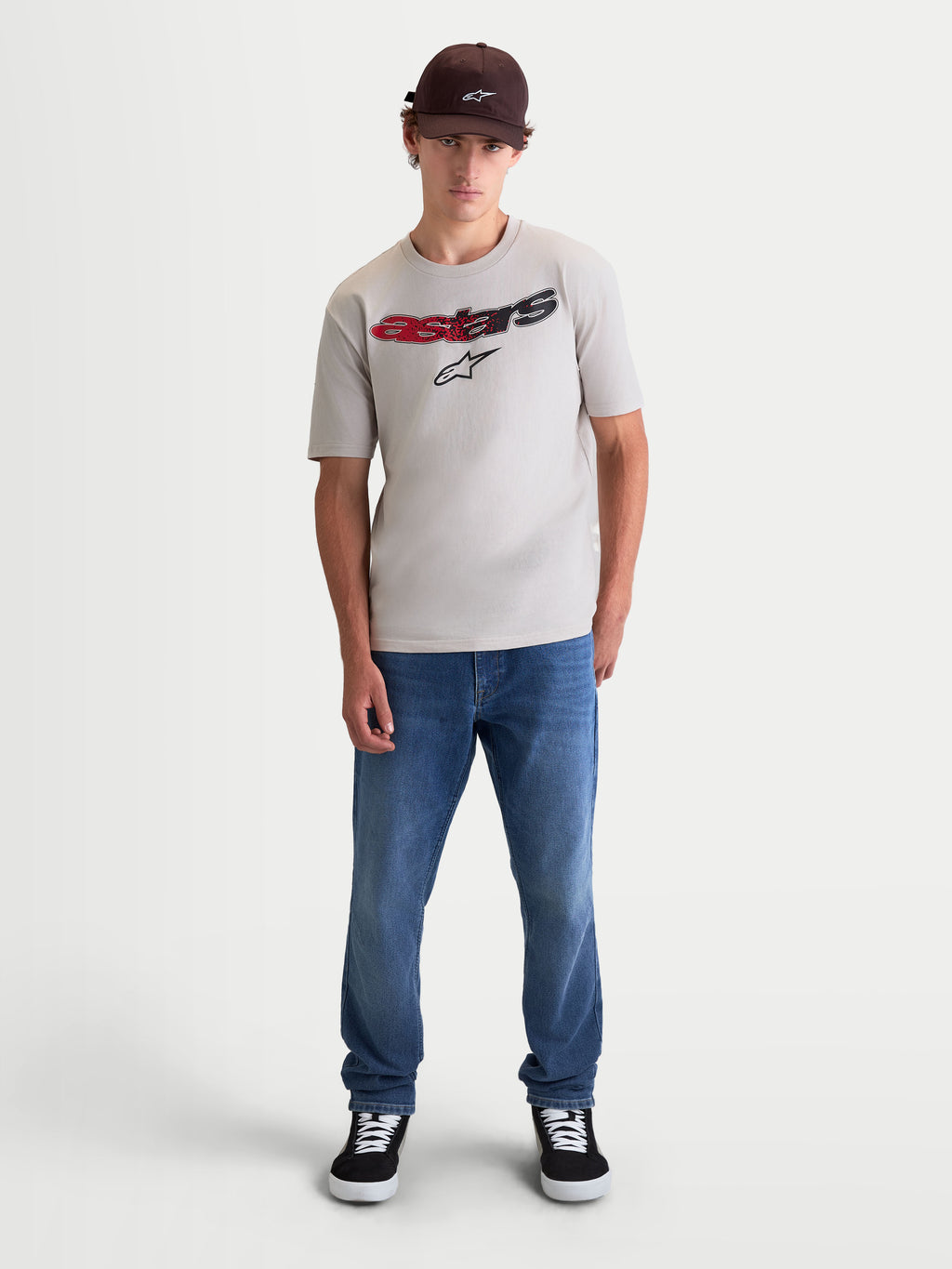 Alpinestars Maglietta Elliptogrit CSF, maglietta da uomo a maniche corte, grigio cemento, con grafica frontale Astars curva e sfumatura rosso-nera, stampa soft-touch in misto cotone, stile lifestyle ispirato al motorsport, indossata da un modello.