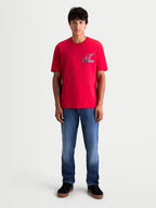 Alpinestars Maglietta Lineout CSF, maglietta da uomo a maniche corte, rossa, con piccolo logo Astars sul petto, stile sportswear casual, modello che indossa il prodotto con jeans blu