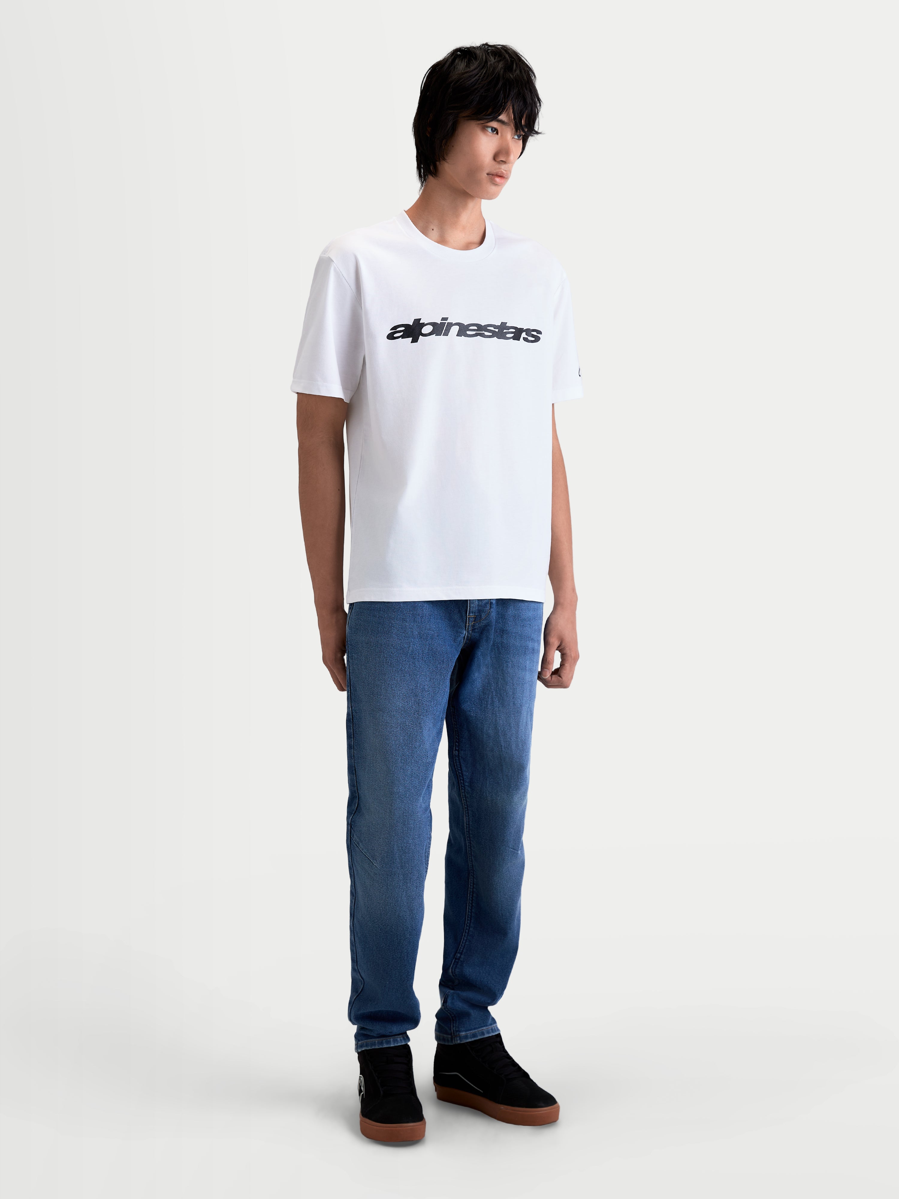 Alpinestars Maglietta Race Wordmark CSF, maglietta a maniche corte da uomo, bianca e nera, con grafica frontale Race ispirata al motorsport, indossata da un modello, stile casual sportswear.