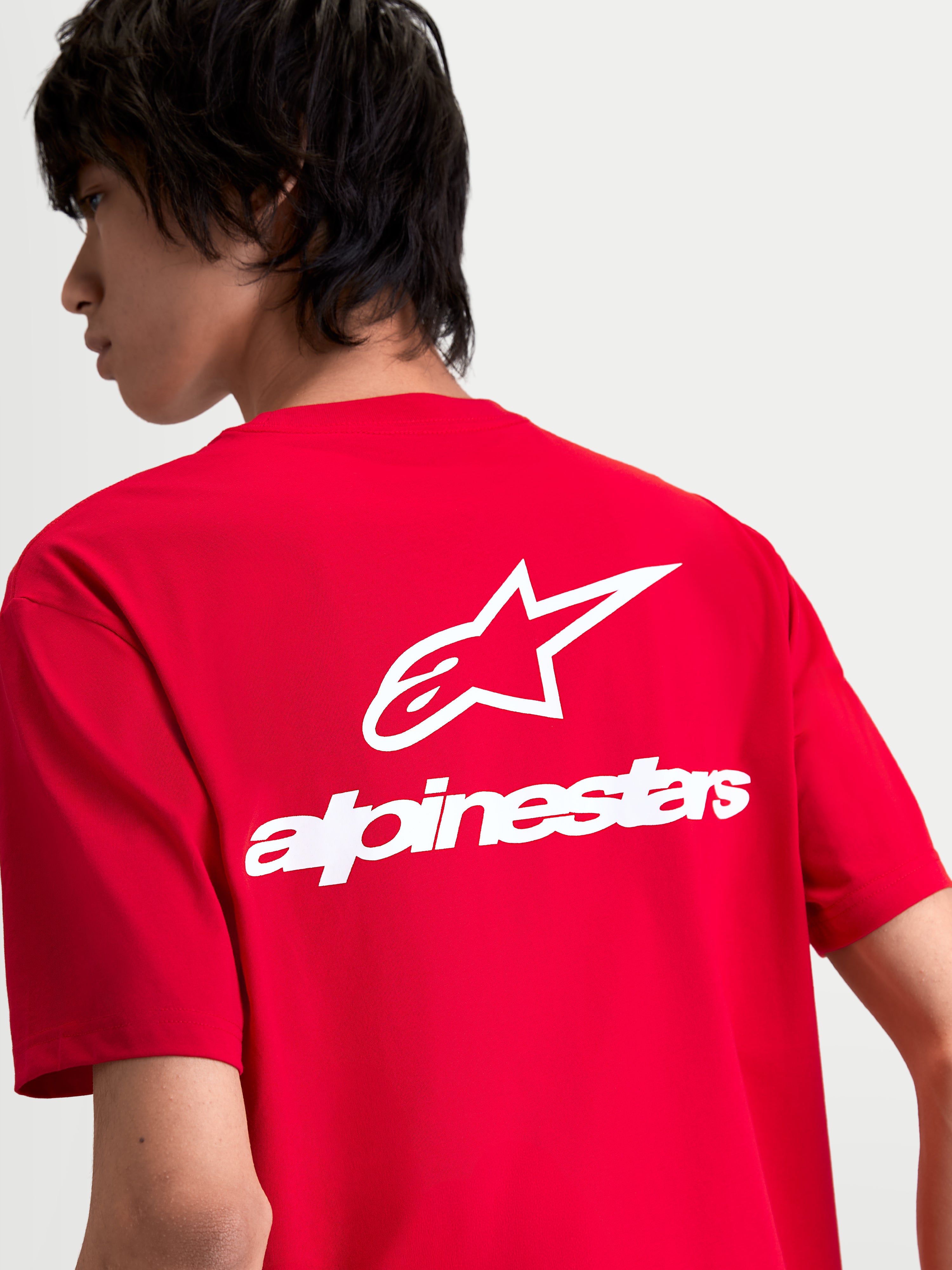 Alpinestars maglietta Combo Back CSF, maglietta a maniche corte, rossa e bianca, vista posteriore su modello con grande logo Astars bianco e scritta sulla schiena, sportswear casual.