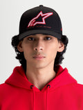 Alpinestars Cappello Lineout, cappello da baseball sportswear con visiera curva, nero con logo Astars ricamato in rosso e bianco e branding One Goal One Vision, vista frontale su modello con felpa rossa, costruzione in twill strutturato
