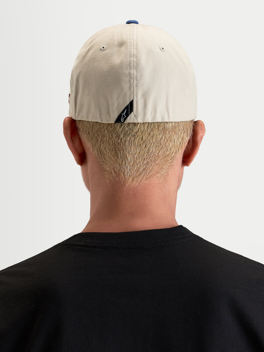 Alpinestars Cappello County Canvas, cappello casual sportswear da uomo, vista posteriore indossato da un modello per mostrare la vestibilità flex-back e il dettaglio del logo sul retro, color sabbia e blu, in tessuto oxford peached