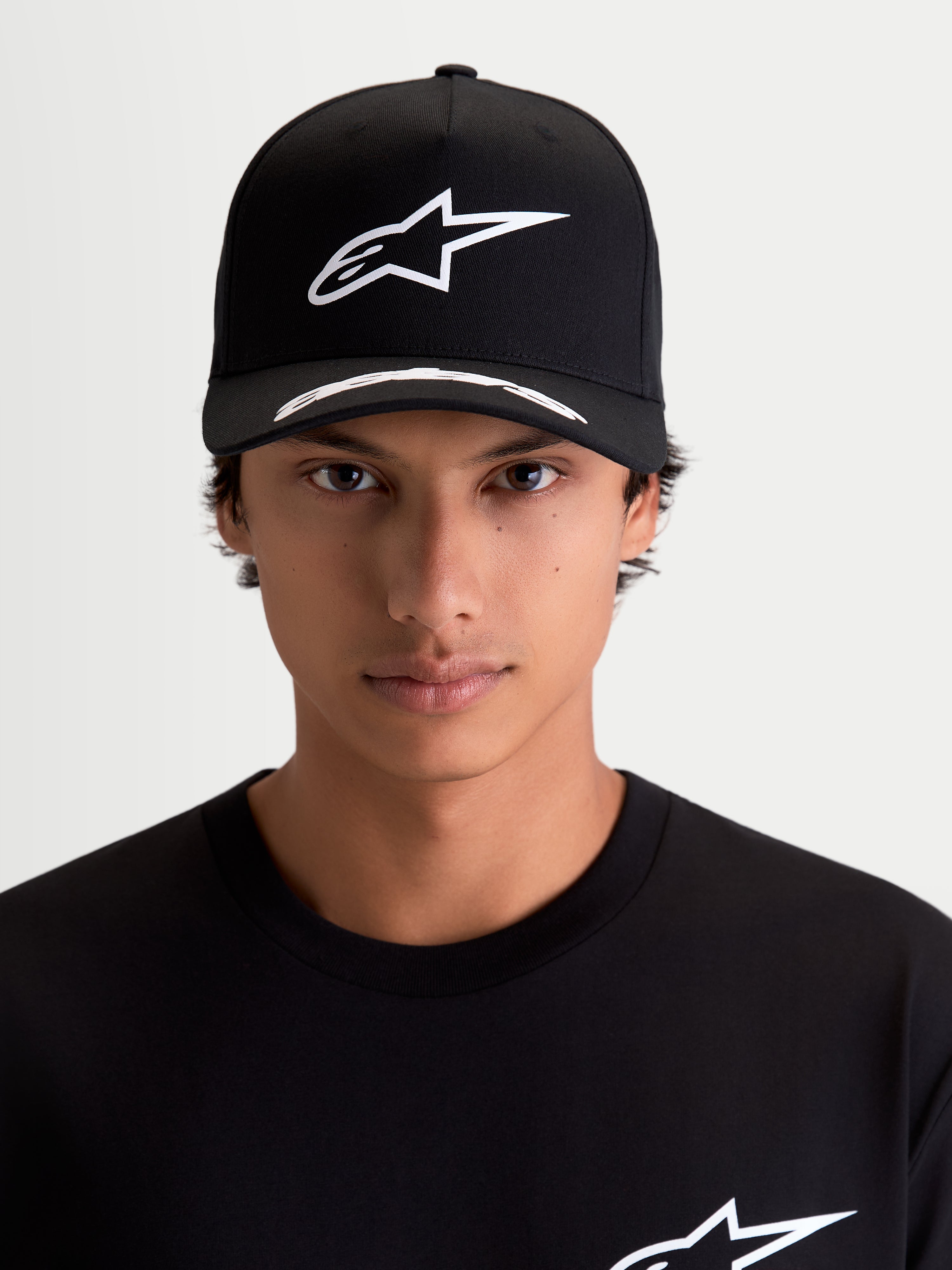 Alpinestars Cappello Arclight, cappello sportswear motorsport, nero e bianco, logo Astars bianco in puff-print sulla corona strutturata e visiera curva con dettagli, in tessuto twill, vista frontale su modello