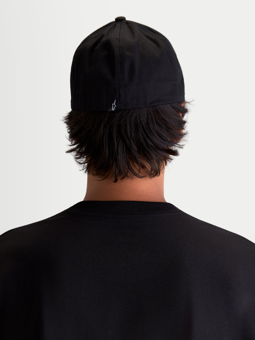Alpinestars Cappello Arclight, cappello sportswear da baseball, vista posteriore su modello, nero con piccolo logo Astars bianco ricamato sul retro, corona strutturata e retro flessibile in twill di cotone