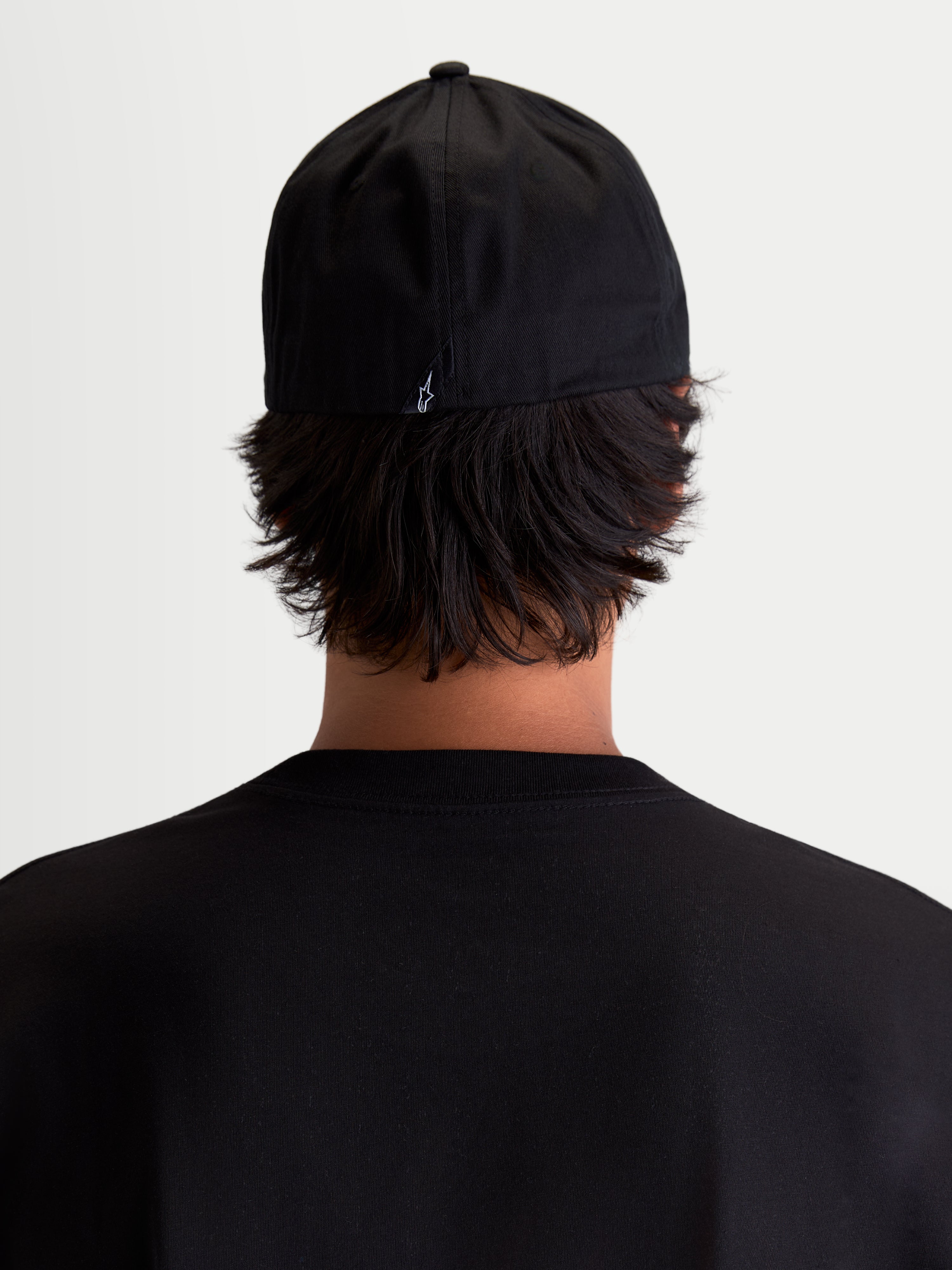 Alpinestars Cappello Arclight, cappello sportswear da baseball, vista posteriore su modello, nero con piccolo logo Astars bianco ricamato sul retro, corona strutturata e retro flessibile in twill di cotone