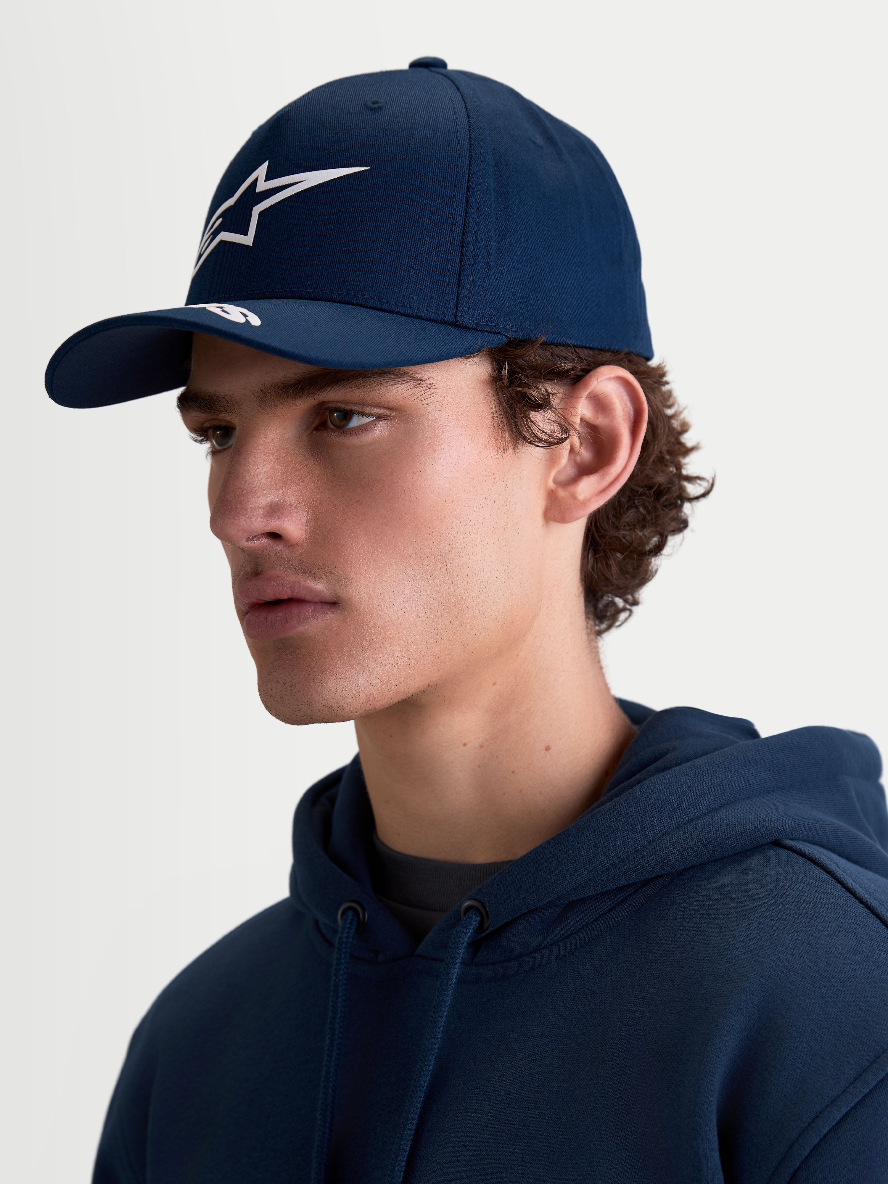 Alpinestars cappello Arclight, cappello sportswear da uomo e donna, blu navy e bianco, in twill di cotone con visiera curva e corona strutturata, branding Astars a rilievo, vista laterale su modello