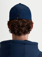 Alpinestars Cappello Arclight, cappello sportswear unisex, blu navy, in resistente twill di cotone con retro flessibile, vista posteriore su modello che mostra il dettaglio dell'etichetta con logo Astars