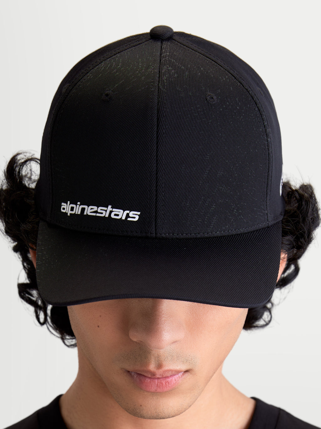 Alpinestars Cappello Points, cappello sportswear nero con visiera curva indossato da un modello, logo testuale Alpinestars bianco sul davanti, realizzato in leggero nylon tactel