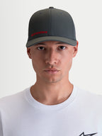 Alpinestars Cappello Points, cappello sportswear con visiera curva per uomo e donna, vista frontale su modello, grigio scuro con logo Alpinestars rosso, tessuto in nylon tactel leggero e vestibilità flex-back