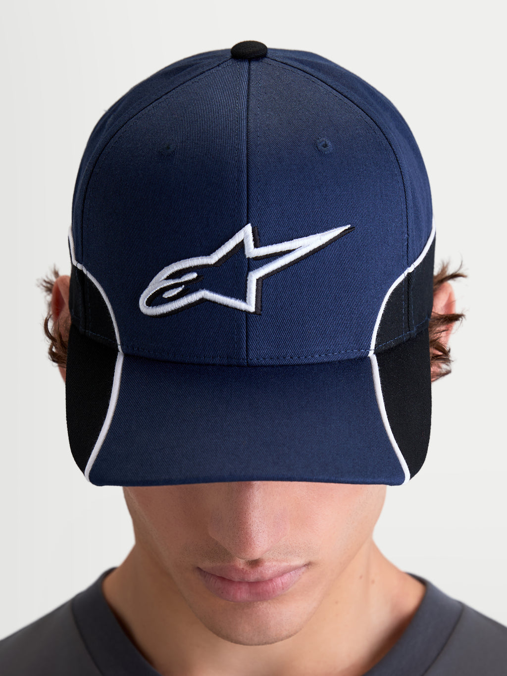 Alpinestars Cappello 500 Snapback, cappello sportswear ispirato al motorsport, unisex, blu navy e nero, con visiera curva e logo Astars bianco ricamato in 3D, piping a contrasto e dettagli cut-and-sew, vista frontale su modello