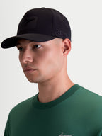 Alpinestars cappello Algo Perf Adjustable, vista su modello di un cappello sportswear nero di ispirazione motorsport con visiera curva, tessuto tecnico con perforazioni laterali per la ventilazione e logo Astars tono su tono.
