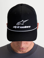Alpinestars Cappello Combo Logo Snapback, cappello sportswear casual indossato da un modello, nero e bianco, corona strutturata, visiera curva con cordino decorativo bianco e logo Astars ricamato sul davanti