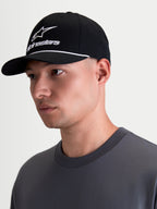Alpinestars Cappello Combo Logo Snapback, cappello sportswear lifestyle, nero e bianco, visiera curva, corona strutturata con ricamo logo combo Astars bianco e dettaglio cordino, indossato da un modello in vista di profilo.