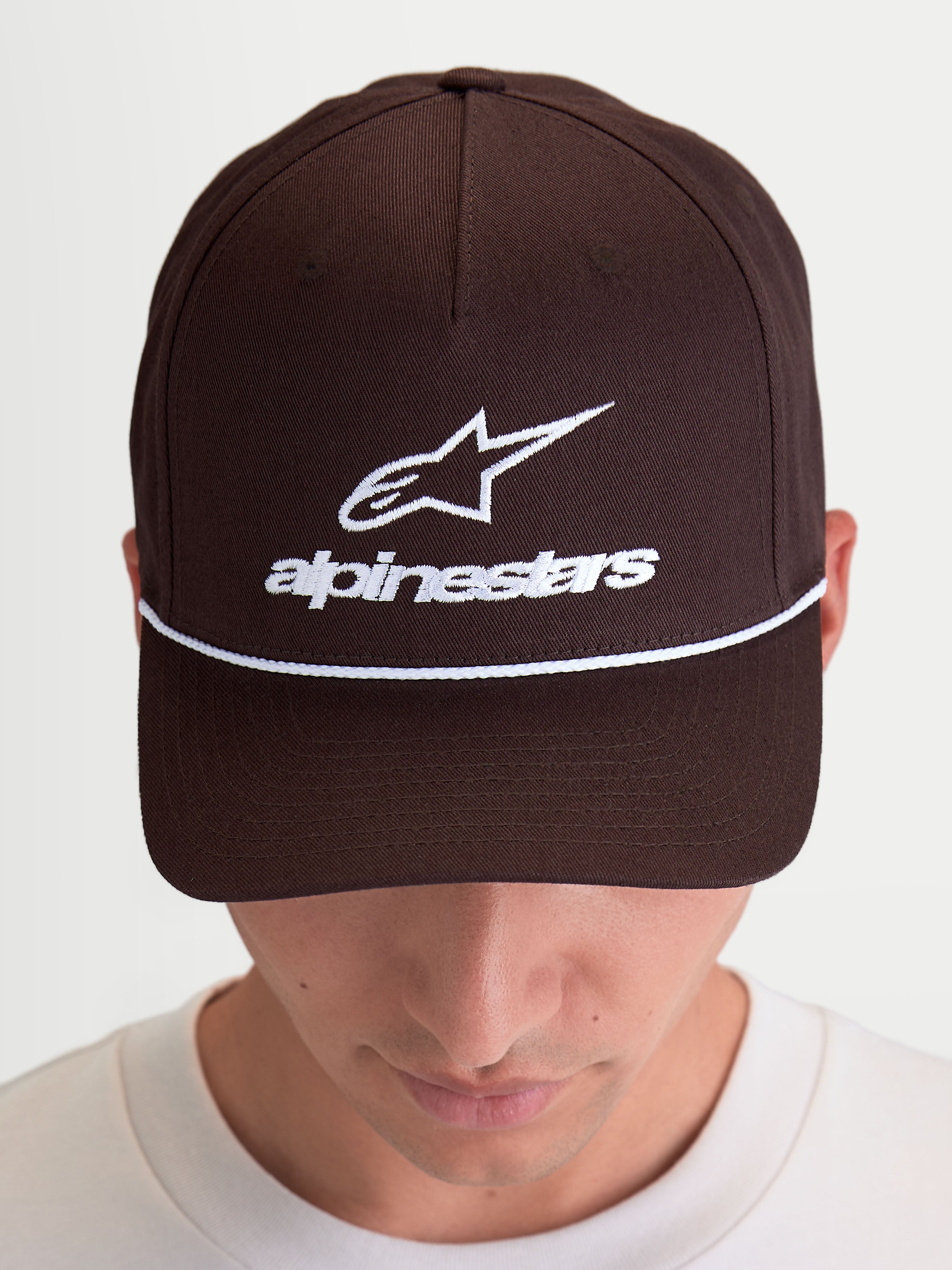 Alpinestars Cappello Combo Logo Snapback, cappello casual sportswear, marrone con ricamo bianco, logo Astars e scritta frontale, visiera curva e corona strutturata, twill di cotone, indossato da un modello