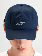 Alpinestars Cappello Dylan Dad, cappello sportivo casual indossato da un modello, blu con visiera curva e logo Astars ricamato in bianco sul davanti