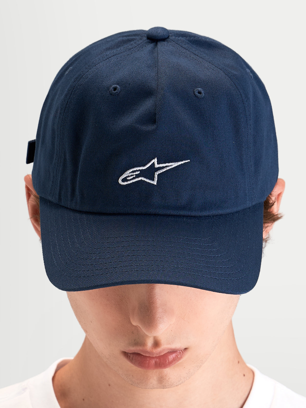 Alpinestars Cappello Dylan Dad, cappello sportivo casual indossato da un modello, blu con visiera curva e logo Astars ricamato in bianco sul davanti