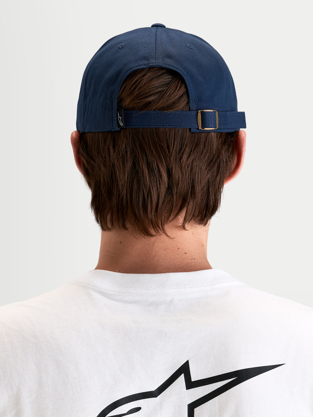 Alpinestars Cappello Dylan Dad, cappello sportswear casual in blu navy, vista posteriore che mostra la chiusura posteriore regolabile con fibbia in metallo e piccola etichetta con logo Astars indossato da un modello