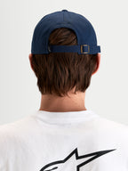 Alpinestars Cappello Dylan Dad, cappello sportswear casual in blu navy, vista posteriore che mostra la chiusura posteriore regolabile con fibbia in metallo e piccola etichetta con logo Astars indossato da un modello