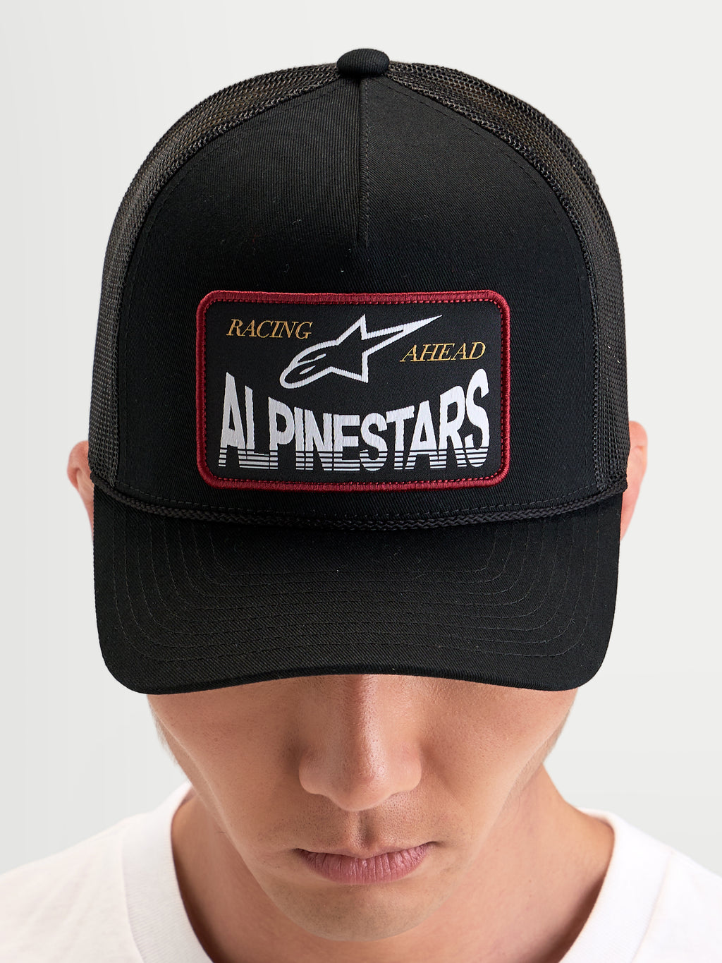 Alpinestars Cappello Hemmings, cappello trucker sportswear indossato da un modello, nero, con pannello frontale in twill, retro in rete traspirante e patch logo frontale