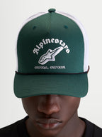 Alpinestars Cappello Baron Trucker, cappellino casual sportswear indossato da un modello, verde e bianco, con visiera curva, frontale strutturato in twill, retro in rete di poliestere traspirante e logo word combo Alpinestars ricamato sul davanti