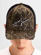 Alpinestars Cappello Thicket Realtree Trucker, cappello trucker sportswear indossato da un modello, mimetico Realtree e nero, visiera curva, corona strutturata e logo Astars ricamato in bianco sul davanti