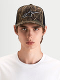 Alpinestars Cappello Thicket Realtree Trucker, cappellino sportswear in camo e nero, indossato da un modello che mostra la corona strutturata e il logo Astars ricamato sul pannello frontale