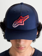 Alpinestars Cappello Meteorite Trucker, cappello sportswear unisex, blu navy con patch logo Astars rossa e bianca a trama ghiaia, corona strutturata e visiera curva, retro in rete traspirante, indossato vista frontale