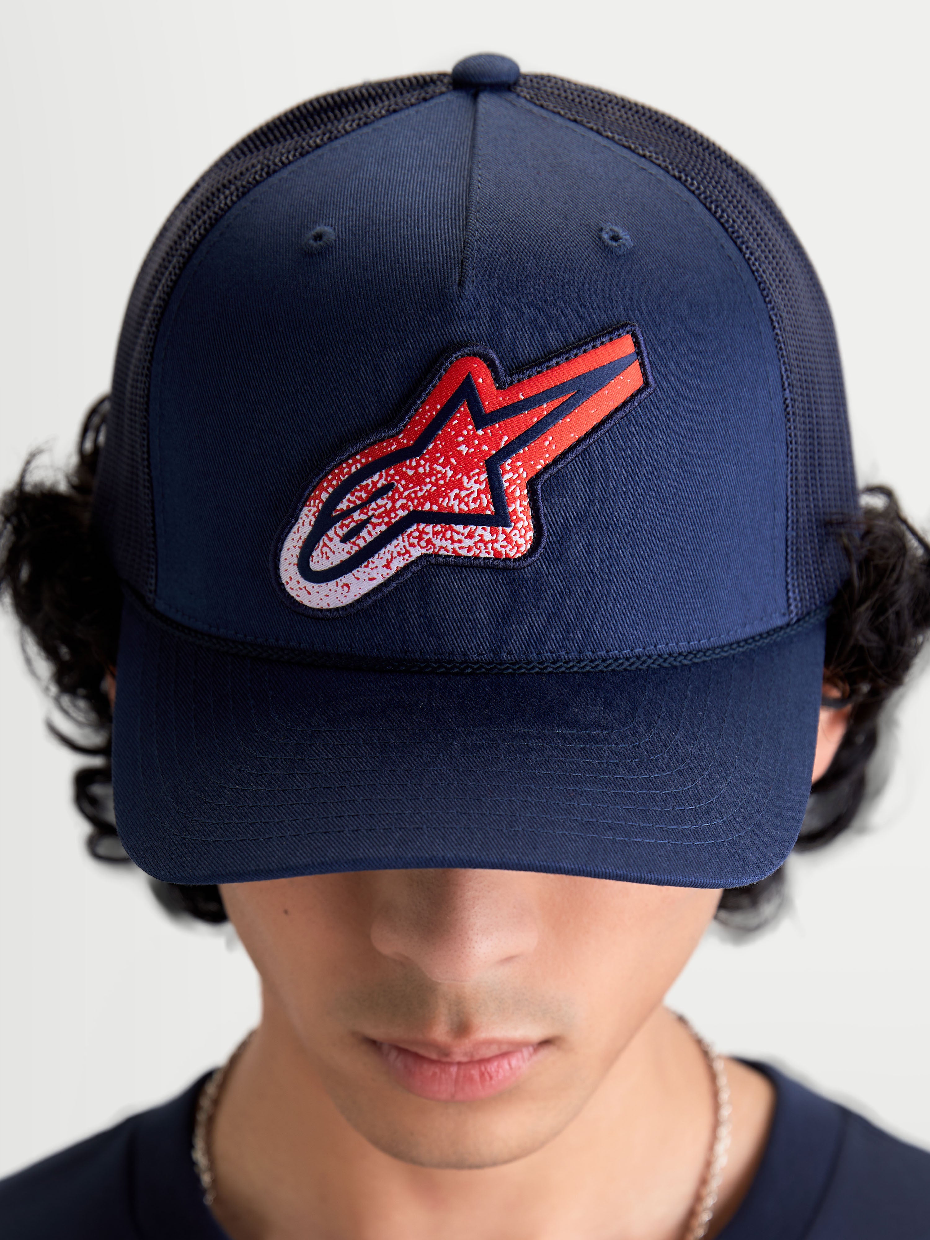 Alpinestars Cappello Meteorite Trucker, cappello sportswear unisex, blu navy con patch logo Astars rossa e bianca a trama ghiaia, corona strutturata e visiera curva, retro in rete traspirante, indossato vista frontale