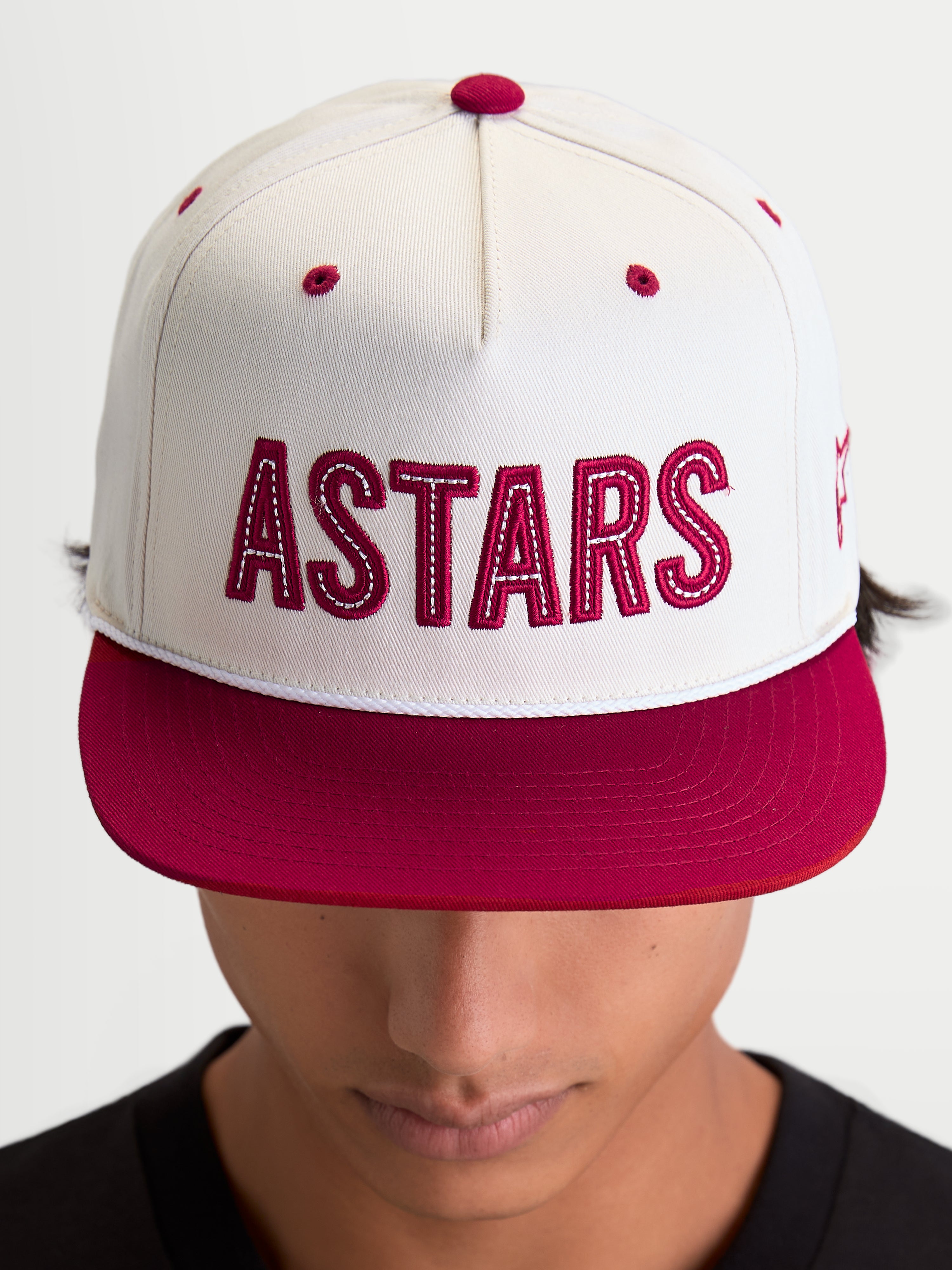 Alpinestars Cappello Stadium Snapback, cappello sportswear con visiera piatta, bianco sporco e rosso, con grande logo Astars frontale applicato con cuciture a contrasto e corona strutturata, indossato da un modello