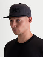 Alpinestars Cappello Stadium Snapback, cappello snapback da uomo stile sportswear, grigio e nero, corona strutturata con visiera piatta, applicazione frontale ASTARS e logo ricamato lateralmente, tessuto in twill di cotone, indossato da un modello
