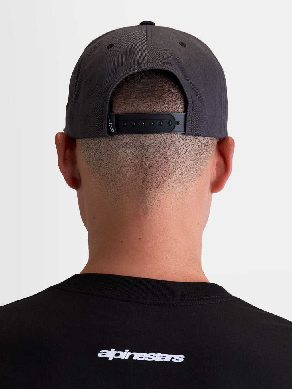 Alpinestars Cappello Stadium Snapback, cappello sportswear grigio scuro e nero, vista posteriore su modello che mostra la chiusura snapback regolabile e la corona strutturata, in resistente twill di cotone