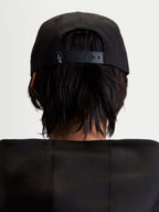 Alpinestars cappello Label Snapback, cappello sportswear nero per uomo e donna, vista posteriore su modello che mostra la chiusura snapback regolabile con piccolo logo bianco, costruzione in twill di cotone strutturato