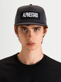 Alpinestars Cappello Ten, cappellino trucker sportswear a visiera piatta in grigio scuro, indossato da un modello, con corona strutturata e patch ricamata con logo Alpinestars sul davanti