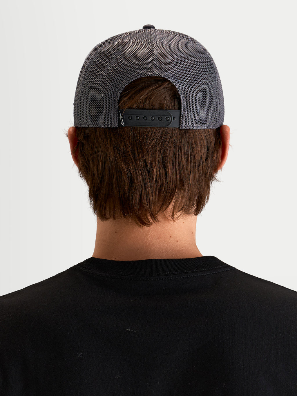 Alpinestars Cappello Ten, cappello trucker sportswear in grigio scuro, vista posteriore su un modello che mostra la chiusura snapback regolabile, i pannelli posteriori in rete e il dettaglio di etichettatura posteriore