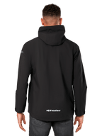 Giacca antipioggia Alpinestars Kascade, giacca impermeabile da uomo, nero, vista posteriore con cappuccio fisso e logo Alpinestars sulla parte inferiore della schiena, abbigliamento sportivo impermeabile casual