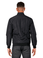 Giacca Alpinestars Precedent, nero, vista posteriore su modello, con iconico motivo trapuntato angolato, polsini e orlo a coste, design motorsport trapuntato ispirato alla F1