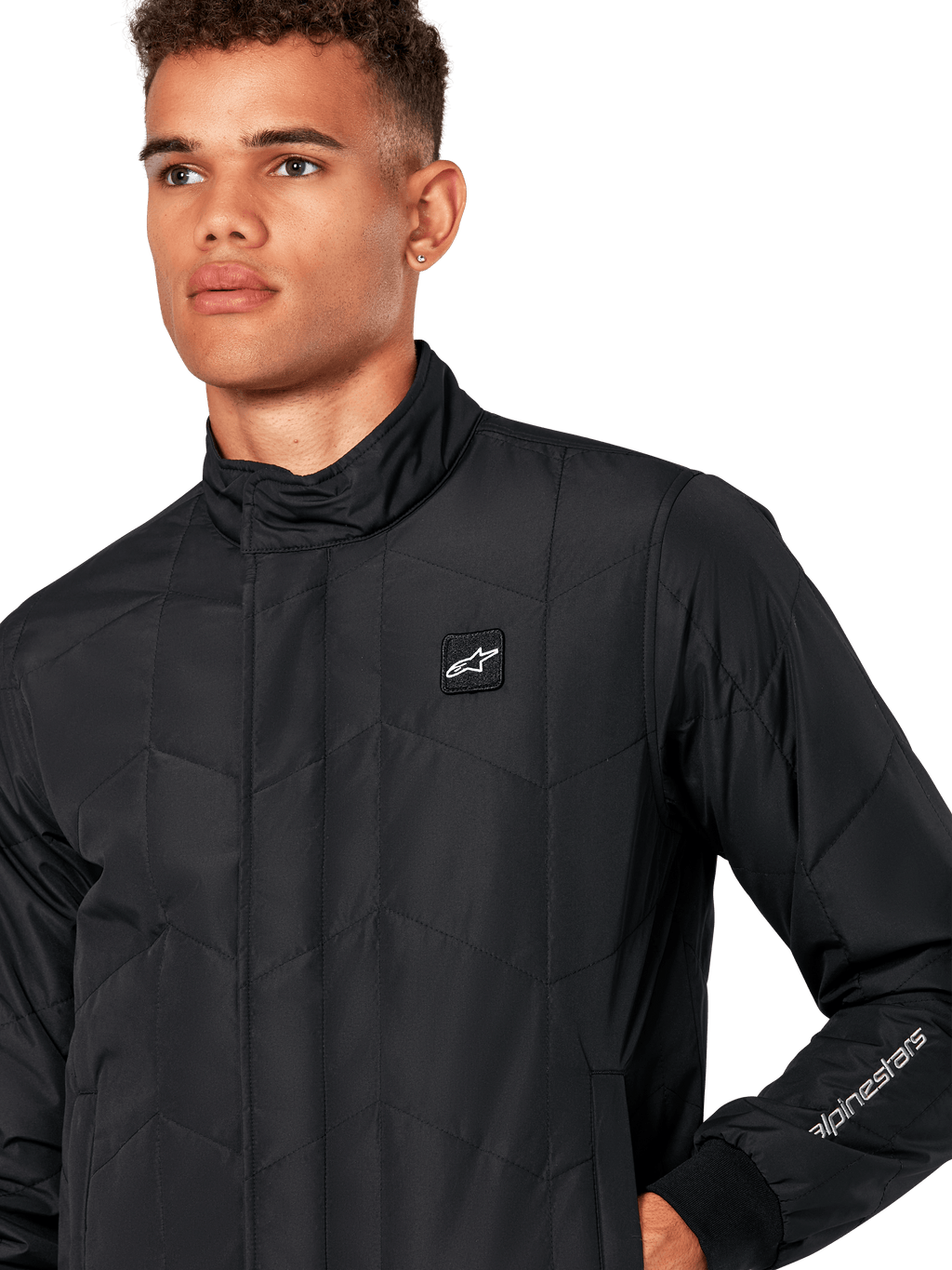 Alpinestars Giacca Precedent, giacca sportiva trapuntata da uomo in nero, primo piano con colletto basso, patch logo sul petto e ricamo sulla manica, caratterizzata da un iconico motivo trapuntato angolato per un look ispirato al motorsport