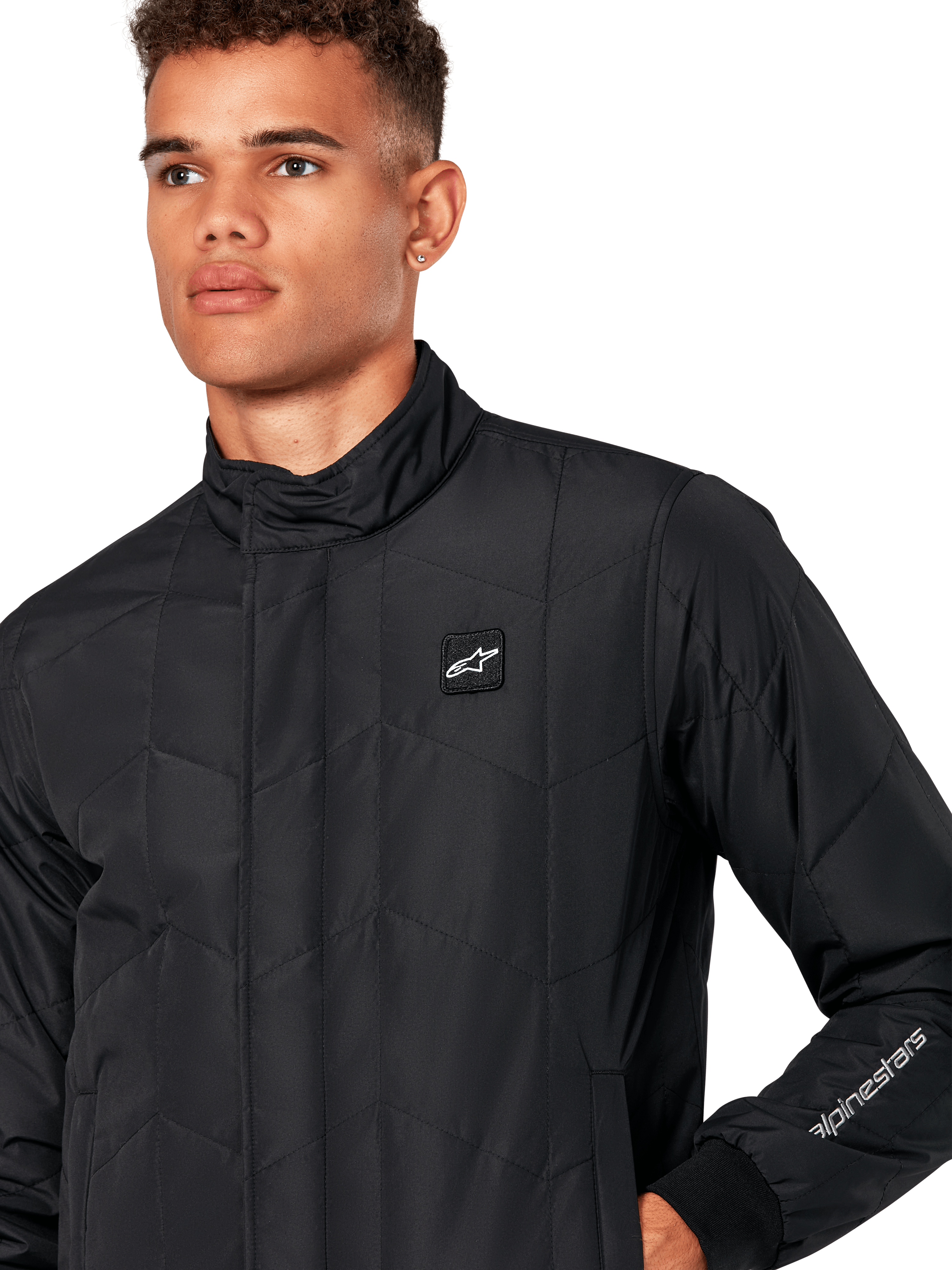 Alpinestars Giacca Precedent, giacca sportiva trapuntata da uomo in nero, primo piano con colletto basso, patch logo sul petto e ricamo sulla manica, caratterizzata da un iconico motivo trapuntato angolato per un look ispirato al motorsport