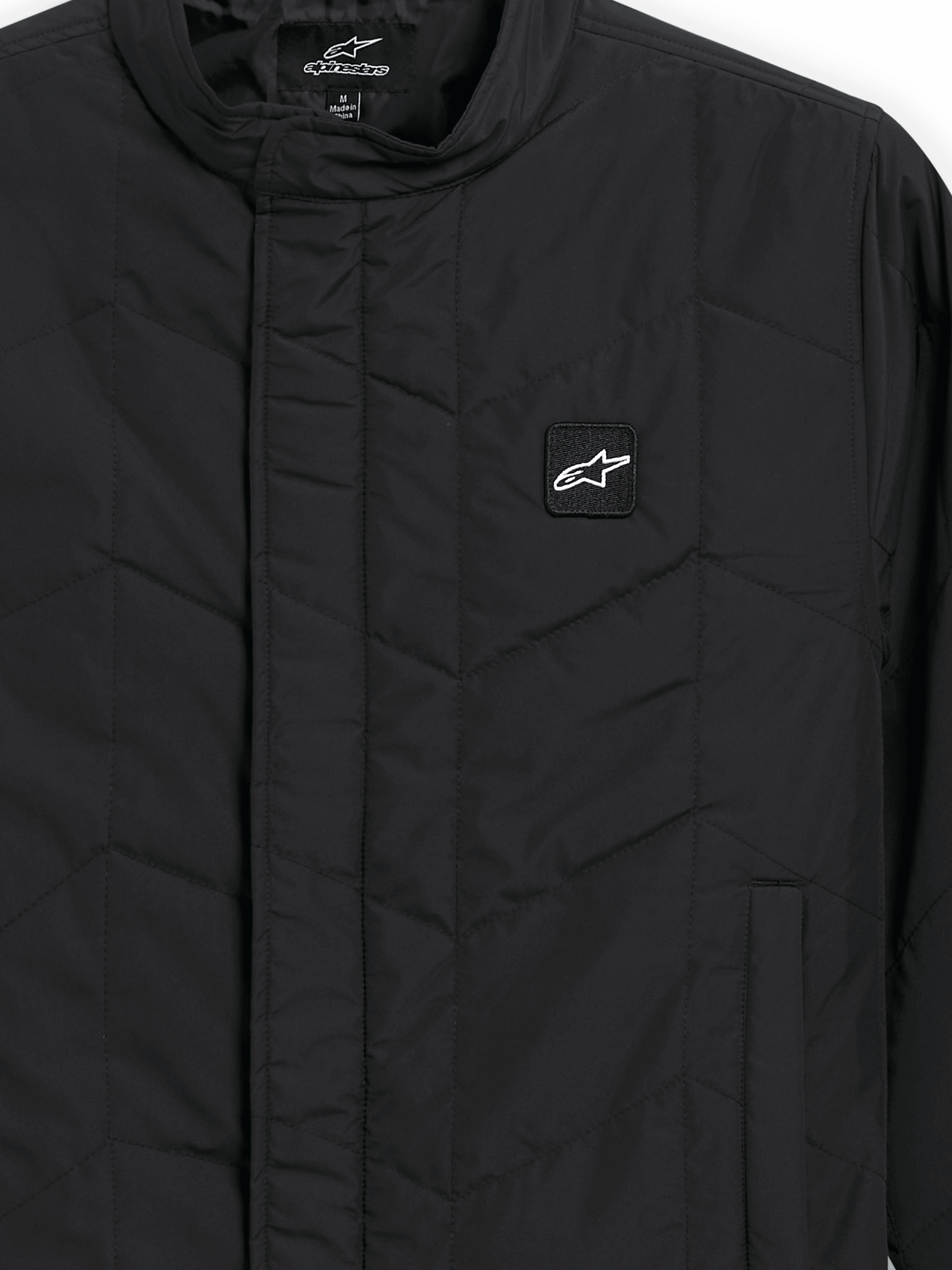 Alpinestars Precedent Jacket, giacca sportswear trapuntata, nero, vista ravvicinata con iconico motivo trapuntato angolato, colletto basso, cerniera frontale coperta e piccola patch con logo sul petto