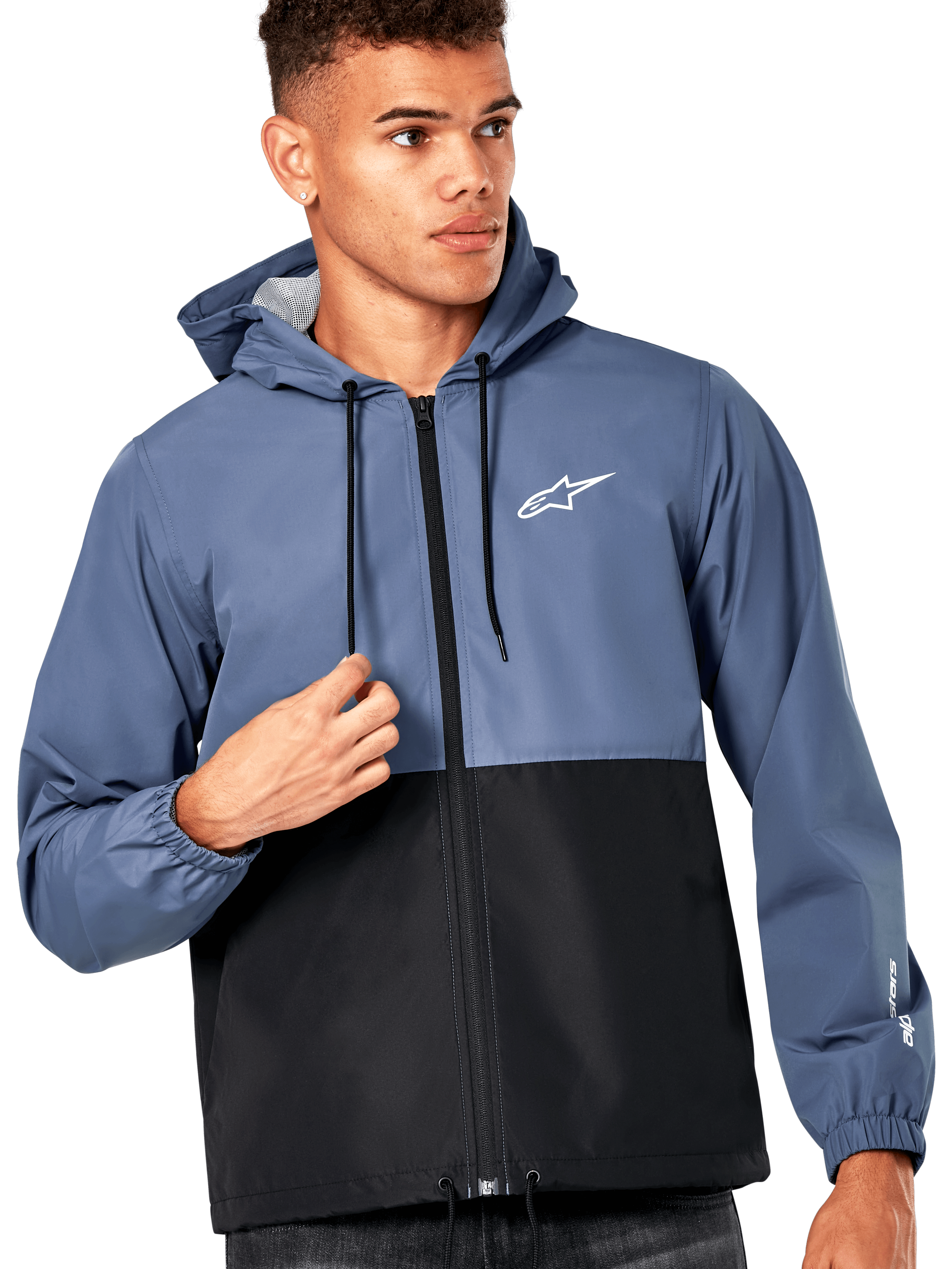 Modello uomo che indossa la giacca frangivento Alpinestars Speeder, design a blocchi di colore blu ardesia e nero, con cappuccio e cordini neri, logo bianco sul petto, giacca a vento casual ispirata al motorsport