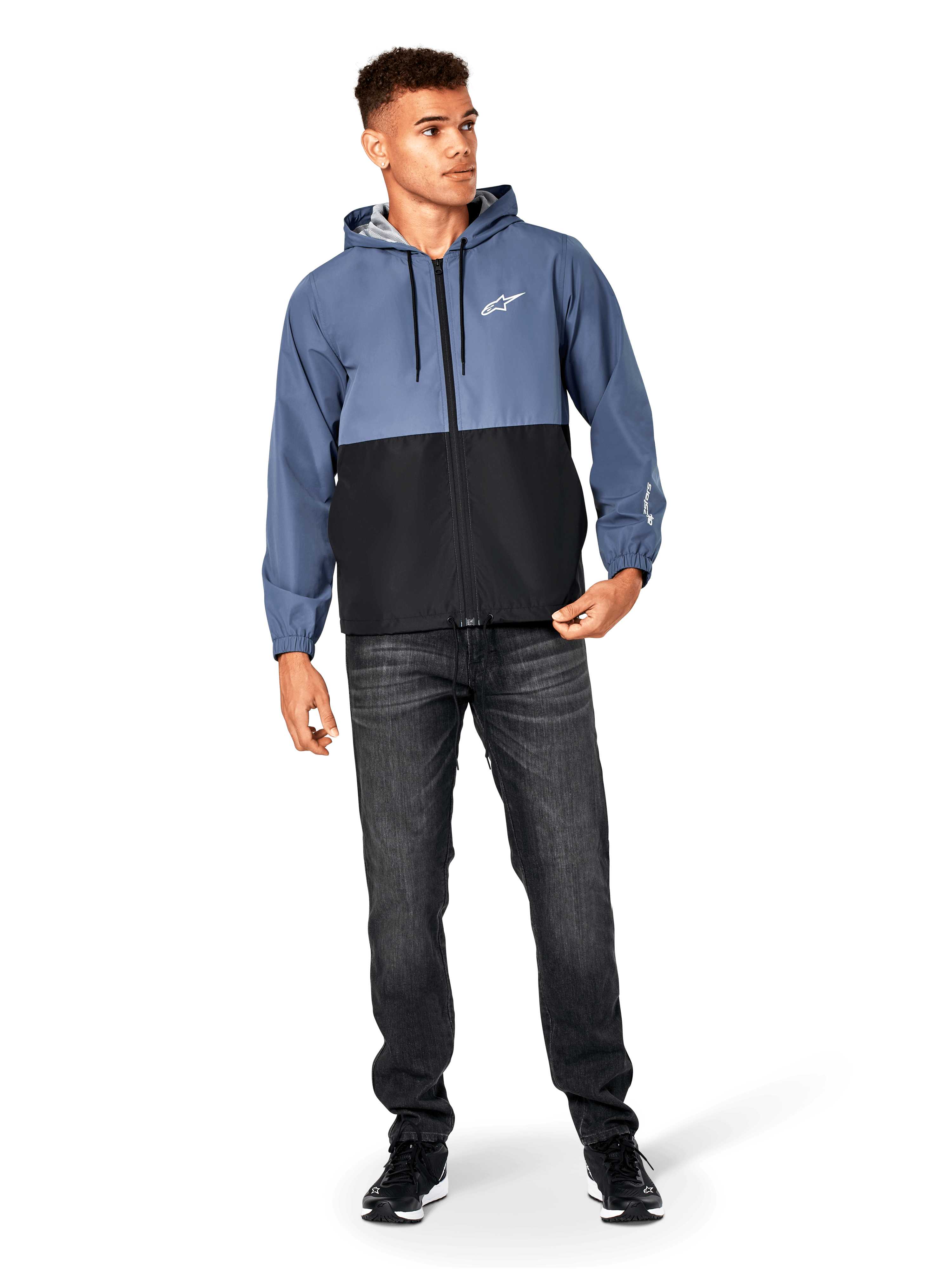 Alpinestars Speeder Windbreaker Jacket, blu ardesia e nero, giacca a vento leggera con cappuccio e fodera in rete, logo con stella bianca sul petto, indossata con jeans neri e sneakers, design casual streetwear motorsport.