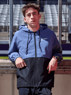 Giacca a vento Alpinestars Speeder, blu ardesia e nero, giacca a vento con cappuccio e design a blocchi, logo bianco sul petto, abbigliamento lifestyle casual indossato in un circuito