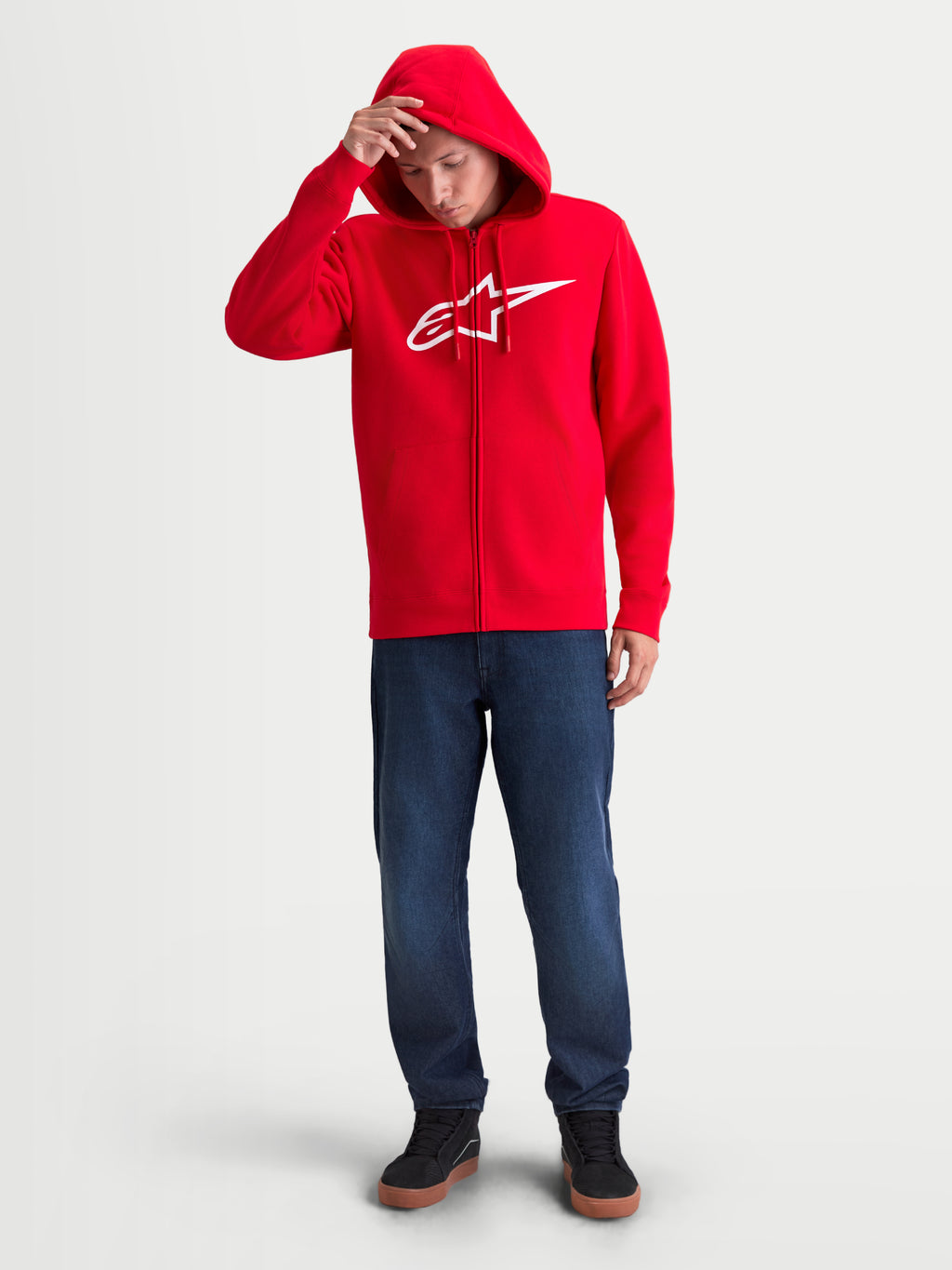 Alpinestars felpa con cappuccio Ageless Zip V3, felpa sportswear da uomo rossa con zip e logo bianco sul petto, cappuccio con cordini e polsini a coste, indossata su modello, stile casual motorsport.