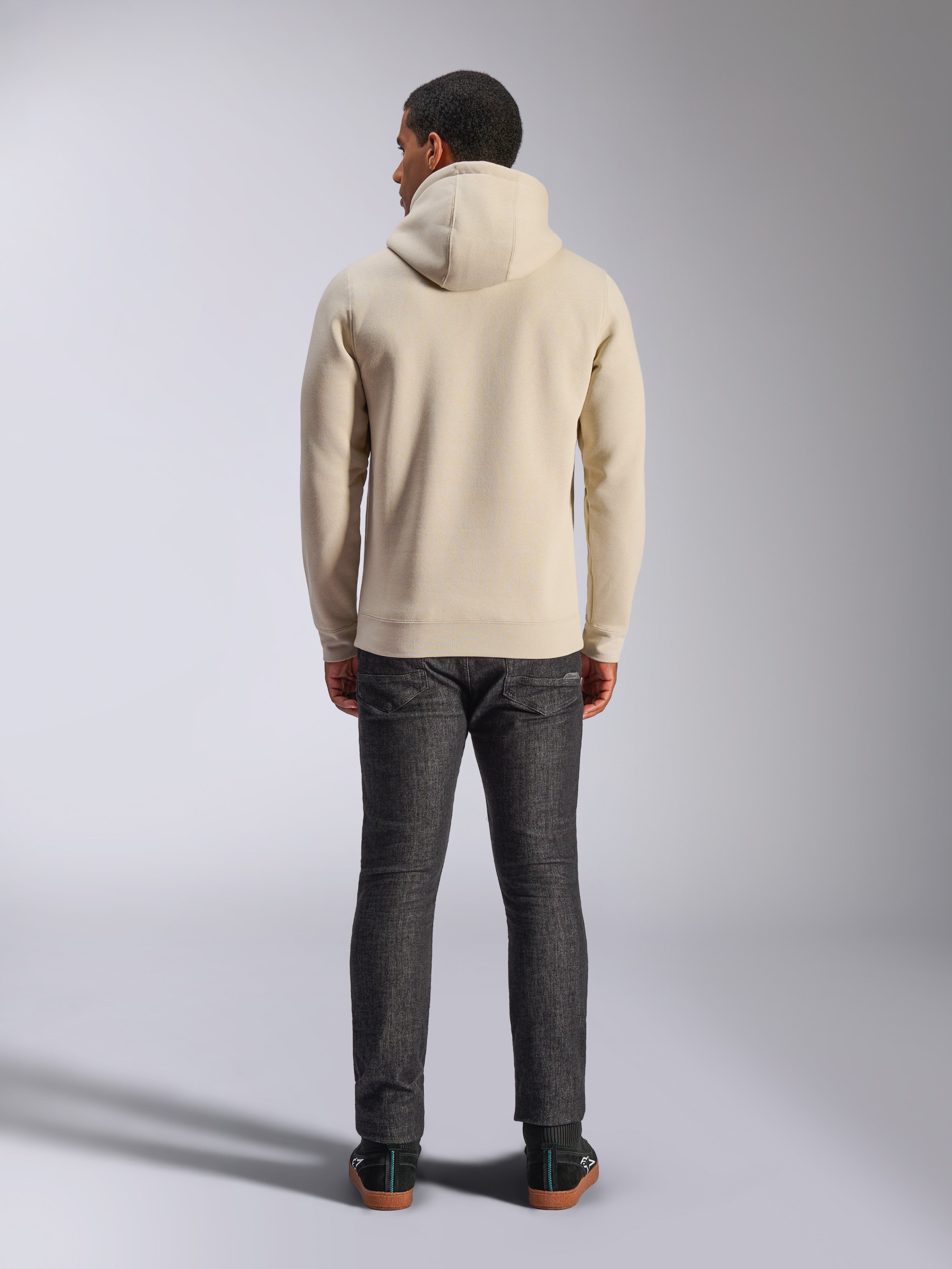 Alpinestars Ageless V3 Hoodie, vista posteriore, felpa con cappuccio bianco panna, abbigliamento casual lifestyle, indossata con jeans grigio scuro, orlo e polsini a costine, design pulito e minimalista