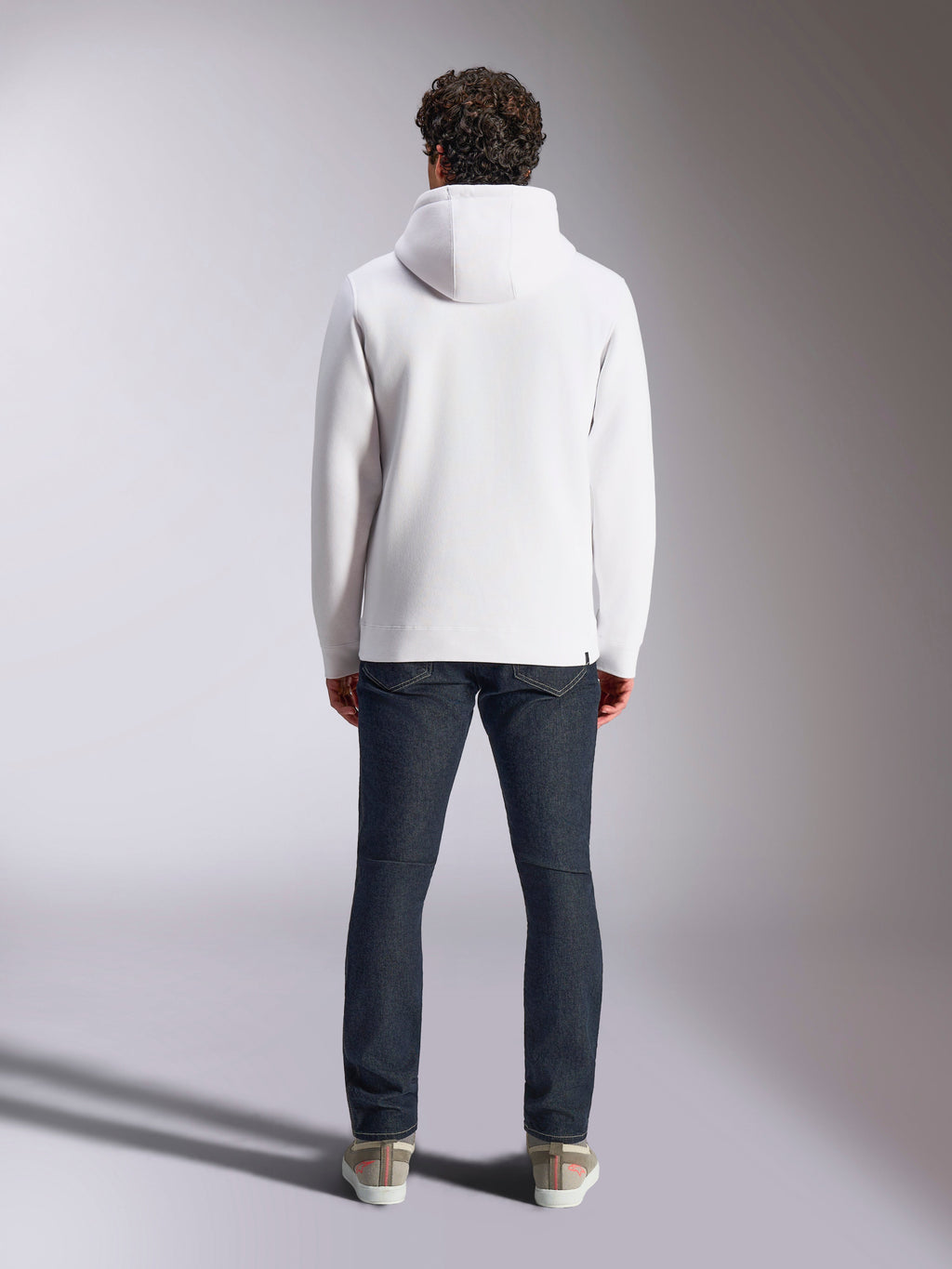 Alpinestars Blaze V3 Hoodie, felpa casual sportiva bianca, vista posteriore della felpa in pile, design pulito con polsini e orlo a costine, abbinata a jeans blu scuro e sneakers, abbigliamento lifestyle moderno ispirato al motorsport