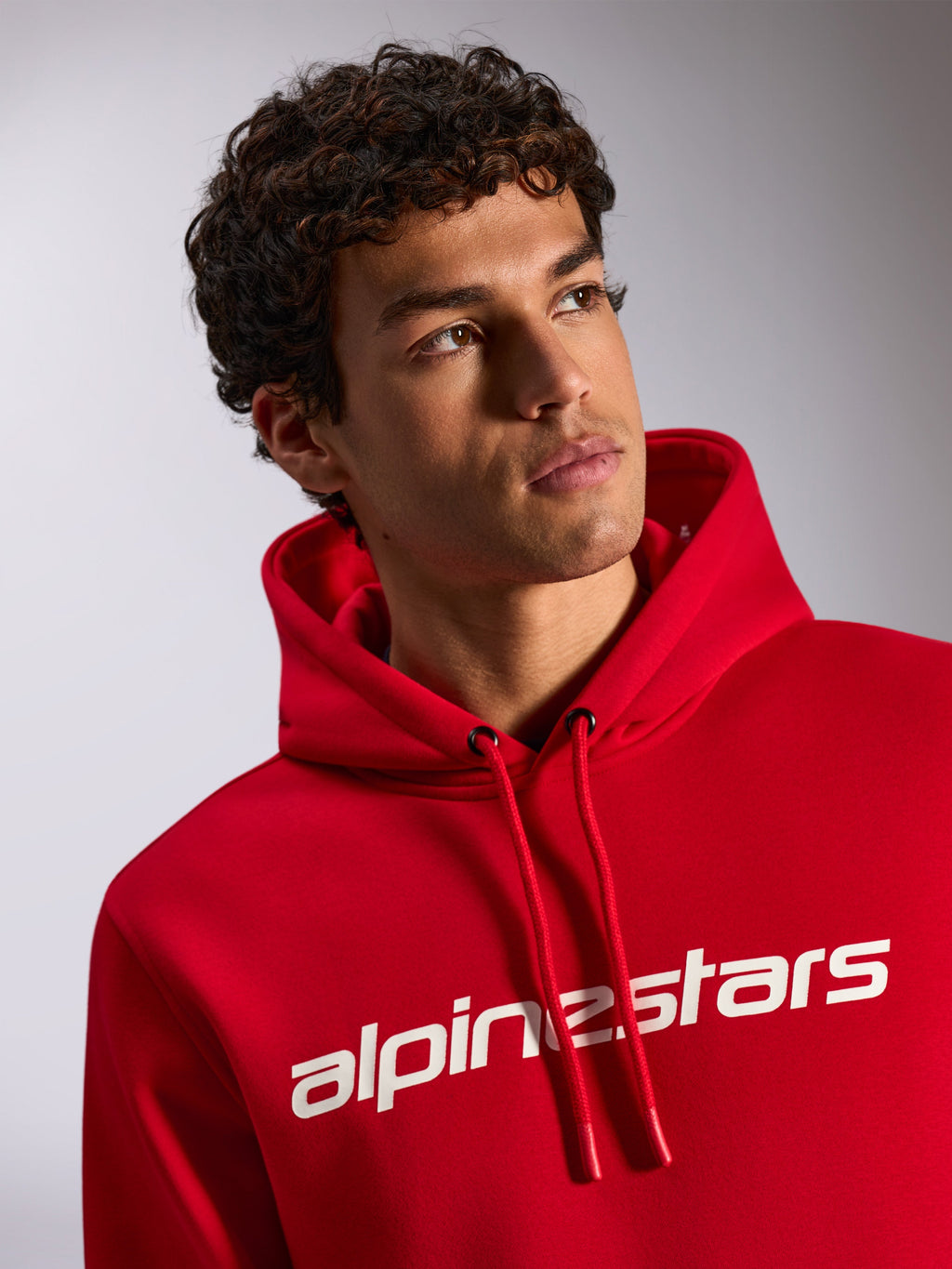 Alpinestars Linear Wordmark V3 Hoodie, felpa casual rossa, logo Alpinestars bianco sul petto, cappuccio con coulisse dalle punte immerse, scatto lifestyle con modello