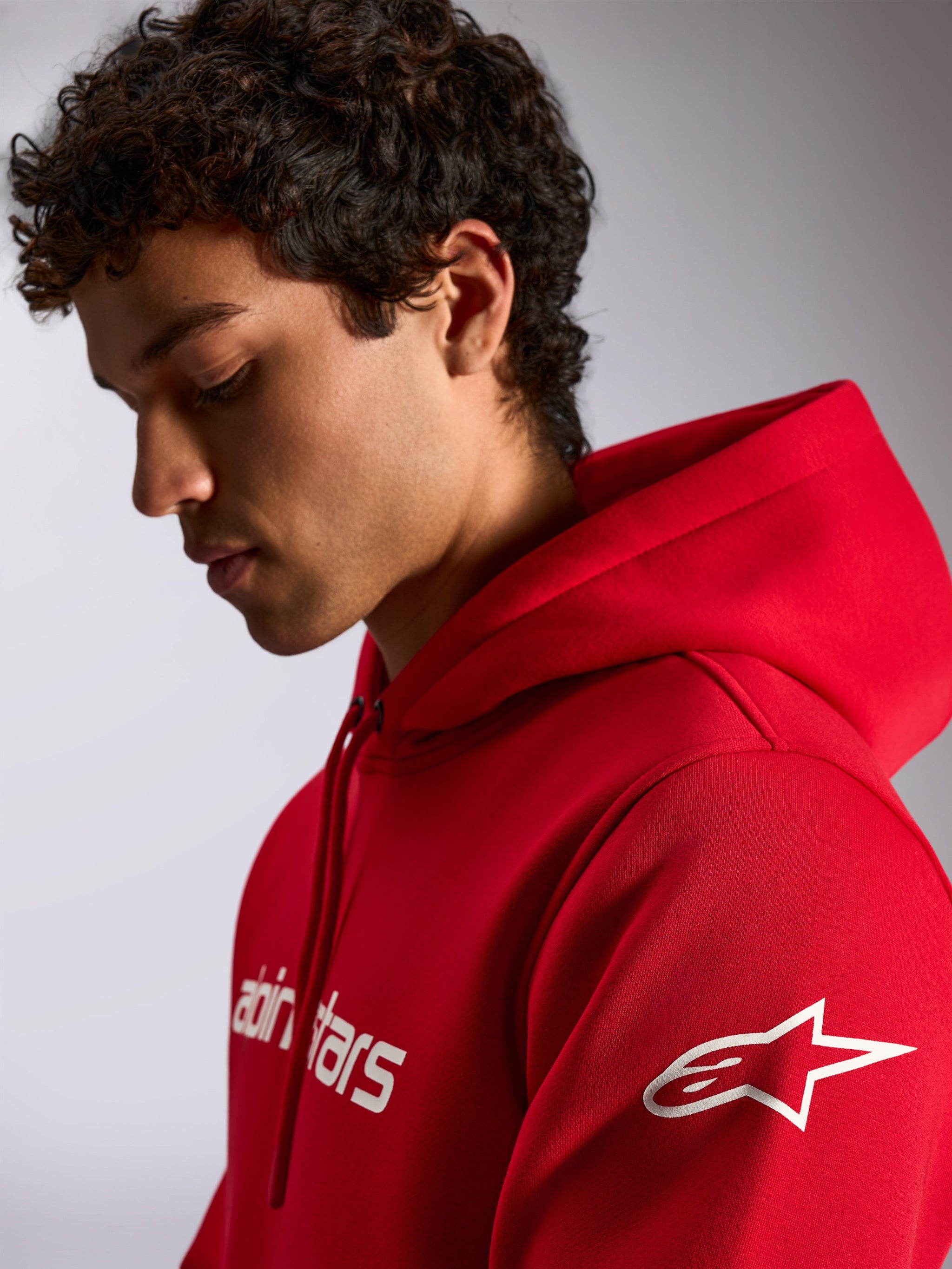 Alpinestars Linear Wordmark V3 Hoodie, rosso, streetwear casual, scritta Alpinestars bianca sul petto e logo a stella Ageless bianco sulla manica, cappuccio con cordino, indossata da un modello
