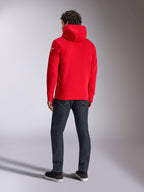Felpa con cappuccio Alpinestars Linear Wordmark V3, felpa casual rossa, vista posteriore con cappuccio e logo Ageless bianco sulla manica, abbinata a jeans blu scuro e scarpe nere, lifestyle motorsport streetwear